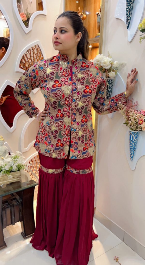 Traditional gold embroidered floral jacket paired with maroon sharara pants, styled in a boutique setup.