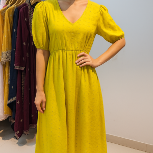 Woman wearing a bright yellow puff sleeve midi dress in boutique setting
